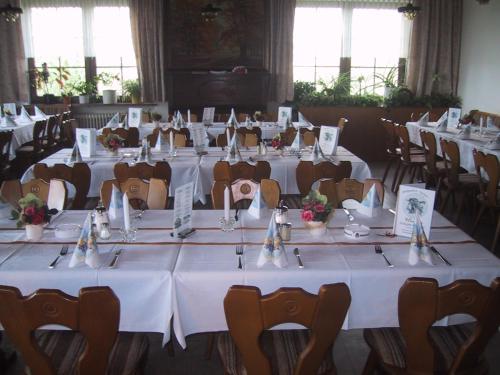 レーゲンにあるBerggasthof Hinhartのテーブルと椅子(白いテーブルクロス付)が備わる客室です。
