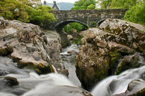 a stone bridge over a river with waterfalls at Royal Oak Hotel in Betws-y-coed