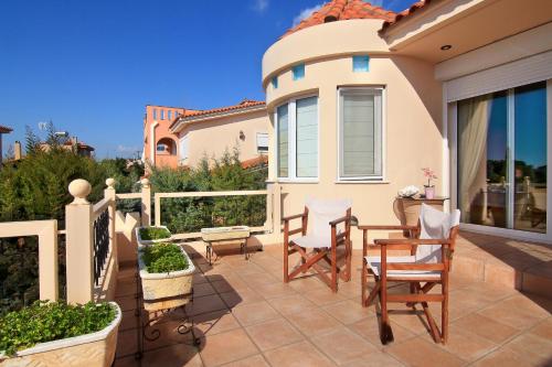 a patio with chairs and a table on a house at Oasis Pool House by GHH in Lagonissi