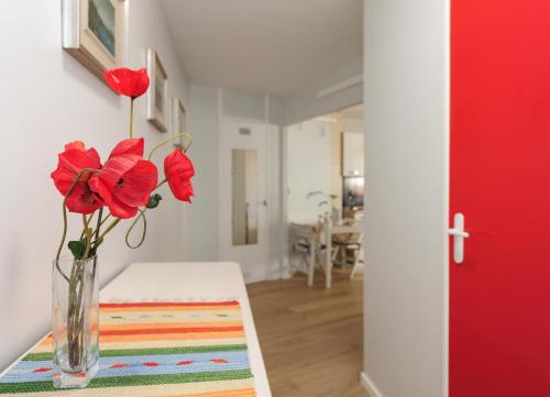 un vase avec des fleurs rouges sur une table dans une pièce dans l'établissement Blue Lagon Five Stars Holiday House, à Nice