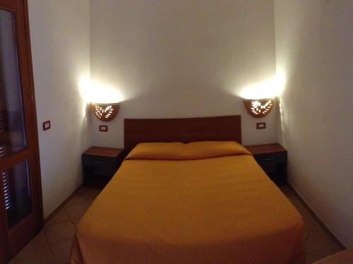 a bedroom with a bed and two lights on the wall at A.I.R. Isola Rossa Borgo di Mare in Isola Rossa