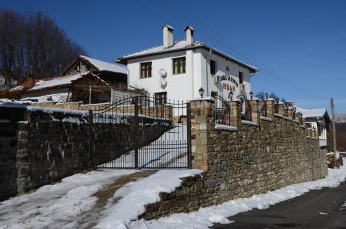 a brick wall with a gate in front of a house at Guest House Ivan in Cherni Osŭm