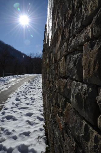 a stone wall with snow on the side of a road at Guest House Ivan in Cherni Osŭm
