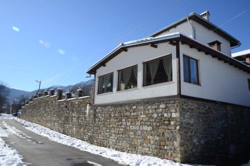 a house on a stone wall in the snow at Guest House Ivan in Cherni Osŭm
