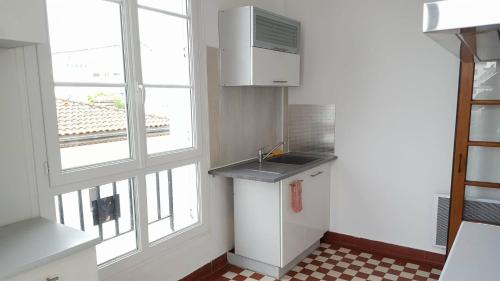 uma pequena cozinha com um lavatório e uma janela em Spacieux 2 pièces dans l'hyper-centre em Royan
