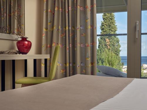 a bedroom with a bed and a window with a view at Koukounaria Hotel & Suites in Alykes