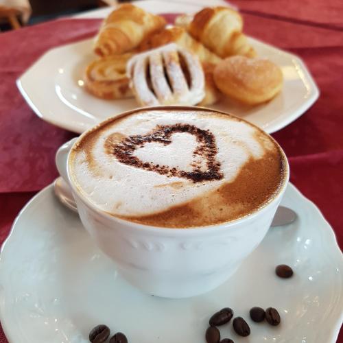 a cup of coffee and a plate of pastries at Villa Adria B&B in Canazei