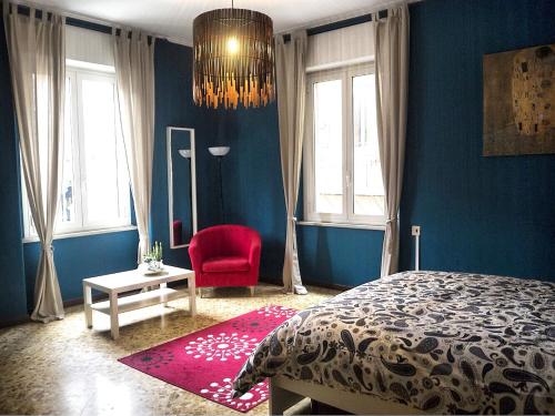 a blue bedroom with a bed and a red chair at B&b Arco Etrusco in Perugia