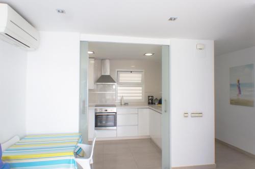 a kitchen with white cabinets and a table and a chair at Apartamento Mediterráneo in Rincón de la Victoria
