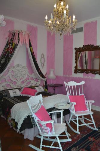 a bedroom with a bed and two chairs and a chandelier at La maison delle favole in Desenzano del Garda