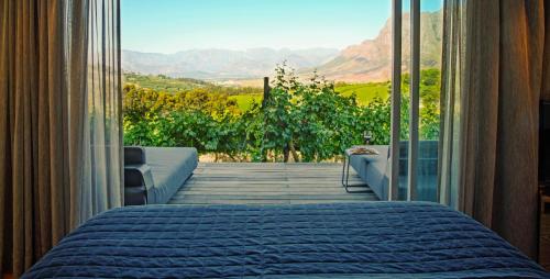 a bedroom with a bed and a window with a view at Clouds Estate in Stellenbosch