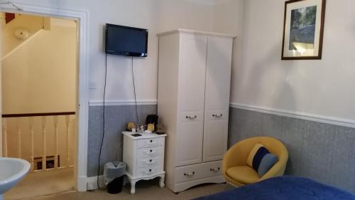 a bedroom with a white cabinet and a tv on the wall at Brooklands Guest House in Bowness-on-Windermere