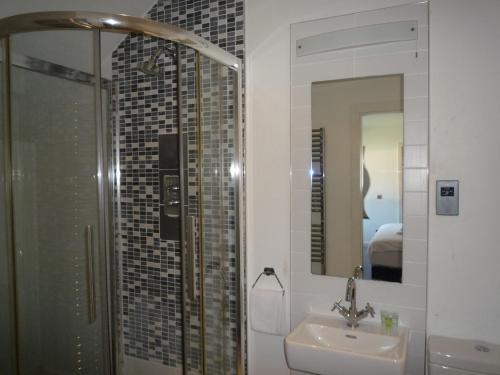 a bathroom with a sink and a shower and a mirror at Castlemartyr Holiday Mews 3 bed in Castlemartyr