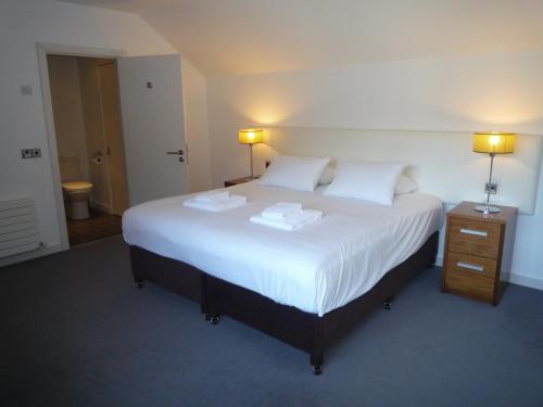 a bedroom with a large white bed with two towels on it at Castlemartyr Holiday Mews 3 bed by Trident Holiday Homes in Castlemartyr