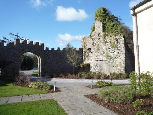 an old castle with an archway in a yard at Castlemartyr Holiday Mews 2 bed by Trident Holiday Homes in Castlemartyr