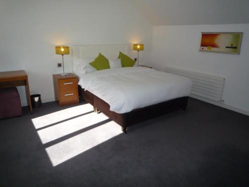 a bedroom with a large bed with white sheets and green pillows at Castlemartyr Holiday Mews 2 bed in Castlemartyr
