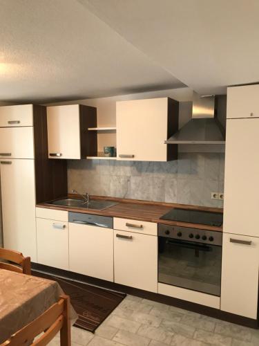 Una cocina con gabinetes blancos y un horno de estufa. en Stadt Apartment, en Günzburg