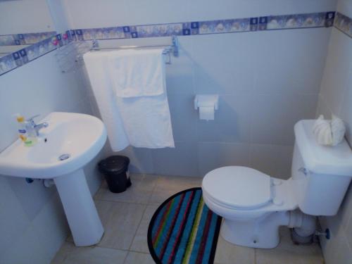 a bathroom with a white toilet and a sink at Sea Breeze Villas Kenya in Diani Beach
