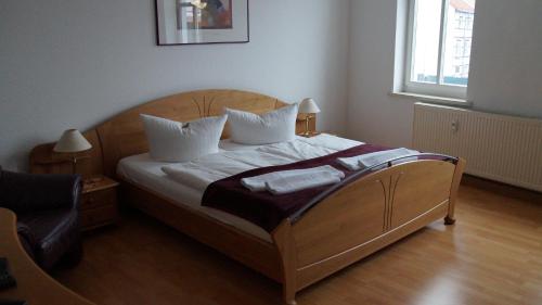 a bedroom with a wooden bed with two pillows at Pension Haus Maria in Mühlhausen