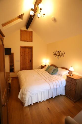 a bedroom with a large white bed and a chandelier at Forda Farm Bed & Breakfast in Holsworthy