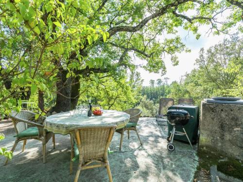 um pátio com uma mesa, cadeiras e comodidades para churrascos em Beautiful riverside villa in Entrecasteaux em Entrecasteaux