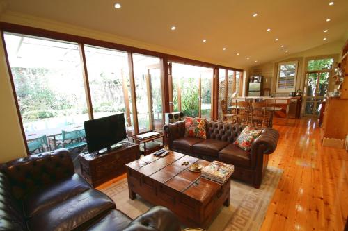 a living room with leather couches and a television at North Adelaide Heritage Cottages & Apartments in Adelaide