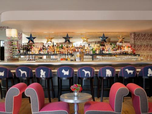 a bar with purple chairs in front of a bar at Haymarket Hotel, Firmdale Hotels in London