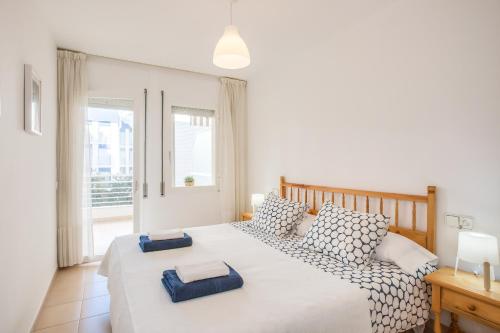 1 dormitorio con 1 cama con 2 almohadas en Lets Holidays White apartment with terrace, ac & parking, near beach, en Tossa de Mar