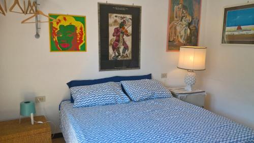 a bedroom with a blue bed and paintings on the wall at SanBart Villetta con Giardino in San Bartolomeo al Mare