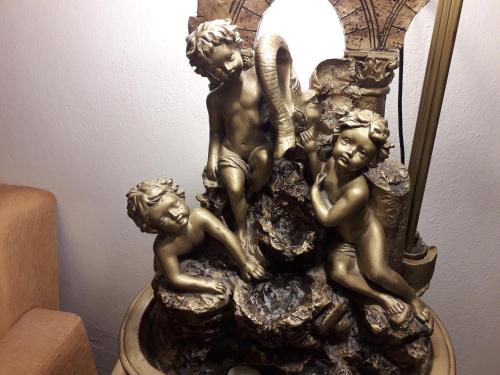 a bronze statue of three children on a lamp at Olympus View Rooms Sauna & Spa in Litochoro