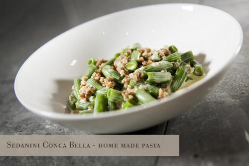 a white bowl of food with meat and vegetables at Conca Bella Boutique Hotel & Wine Experience in Vacallo