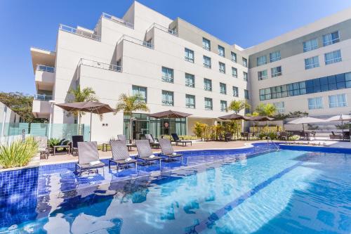 a hotel swimming pool with chairs and a building at eSuites Lagoa Santa in Lagoa Santa