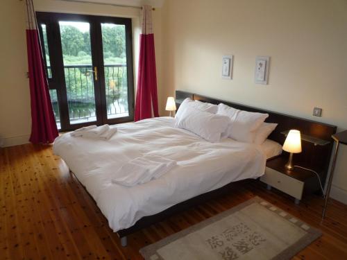 a bedroom with a large bed with white sheets and pillows at Grove Lodge Holiday Homes (2 Bed) in Killorglin