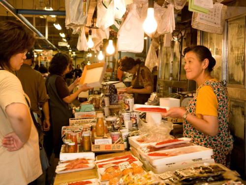 una donna in piedi al bancone di un mercato che vende cibo di Smile Hotel Hachinohe a Hachinohe