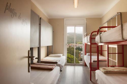 Alberg Costa Brava في يانسا: غرفة بها ثلاثة أسرة بطابقين ونافذة