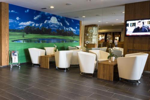 un restaurante con sillas blancas y una pantalla grande en Sand Martin, en Mladá Boleslav