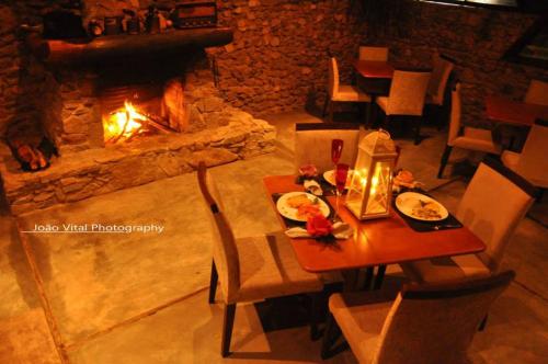 a table and chairs in front of a fireplace at Pousada Pedra Grande in Serra de São Bento
