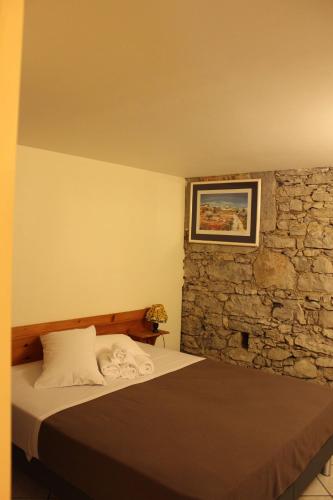 une chambre avec un lit et un mur en pierre dans l'établissement Le Mas De Roux, à Bragassargues