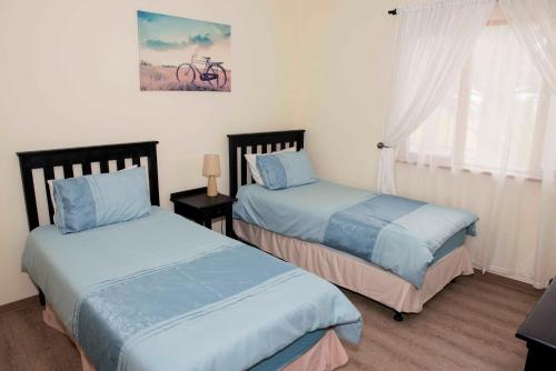 1 dormitorio con 2 camas y una bicicleta en la pared en Good Times Self Catering Apartments, en Swakopmund