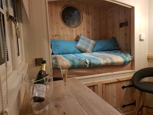 a wine bottle on a table with a bed in a room at Waterside Shepherds Hut in York