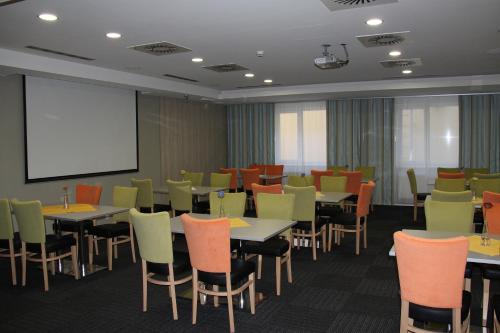 a conference room with tables and chairs and a screen at Buly Aréna in Kravaře