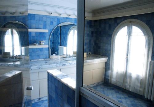 a blue tiled bathroom with two sinks and two mirrors at Casa Diletta in Massa e Cozzile