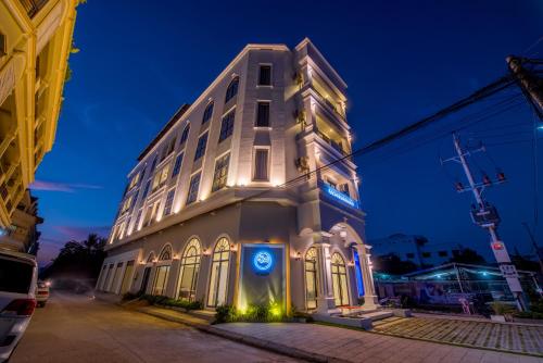 a white building with a blue sign in front of it at Sky Palace Boutique Hotel in Battambang