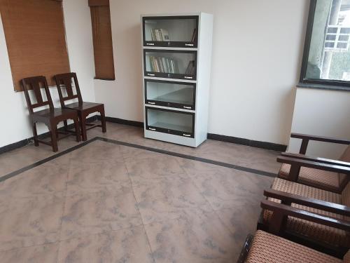 a living room with two chairs and a book shelf at Hotel Meera in Raipur