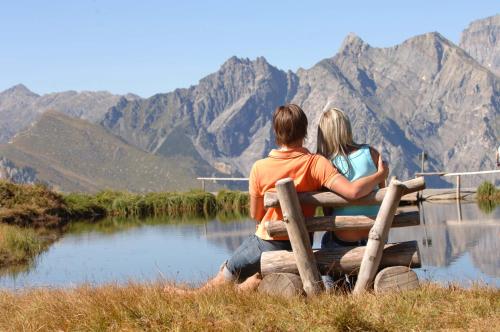 a couple sitting on a bench looking at the mountains at Haus Bazigg in Klösterle am Arlberg
