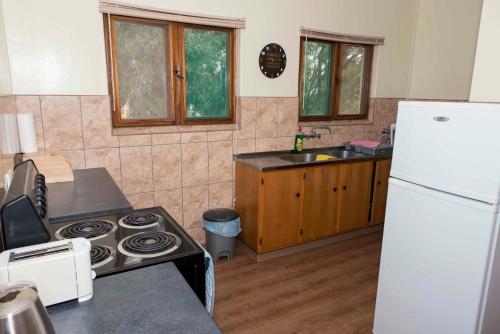 cocina con fogones y nevera blanca en Good Times Self Catering Apartments, en Swakopmund