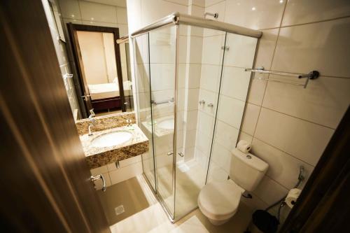 a bathroom with a shower and a toilet and a sink at Hotel London Santarem in Santarém