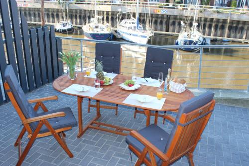 a wooden table and chairs with boats in the water at Ferienhaus Hafenzeit in Cuxhaven