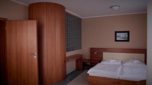 a bedroom with a bed and a wooden cabinet at Buly Aréna in Kravaře