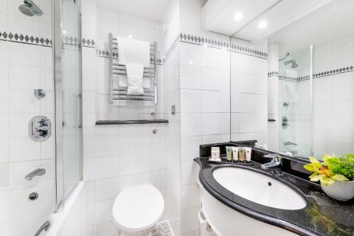 e bagno con lavandino, servizi igienici e doccia. di Millennium Hotel London Knightsbridge a Londra